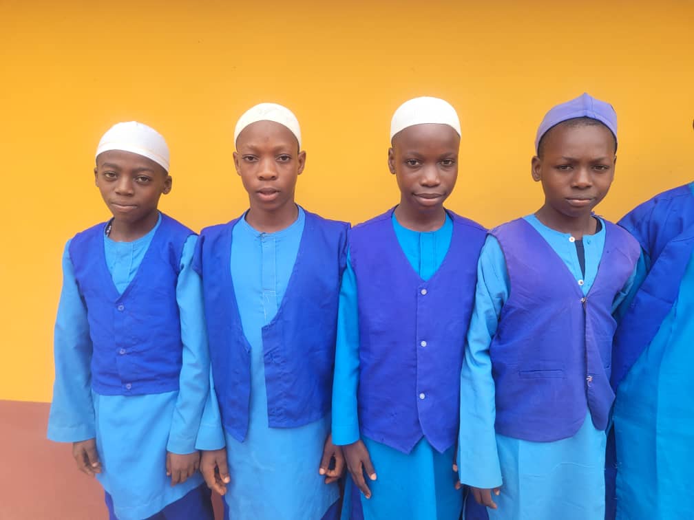 Male students in traditional Islamic caps and blue uniforms